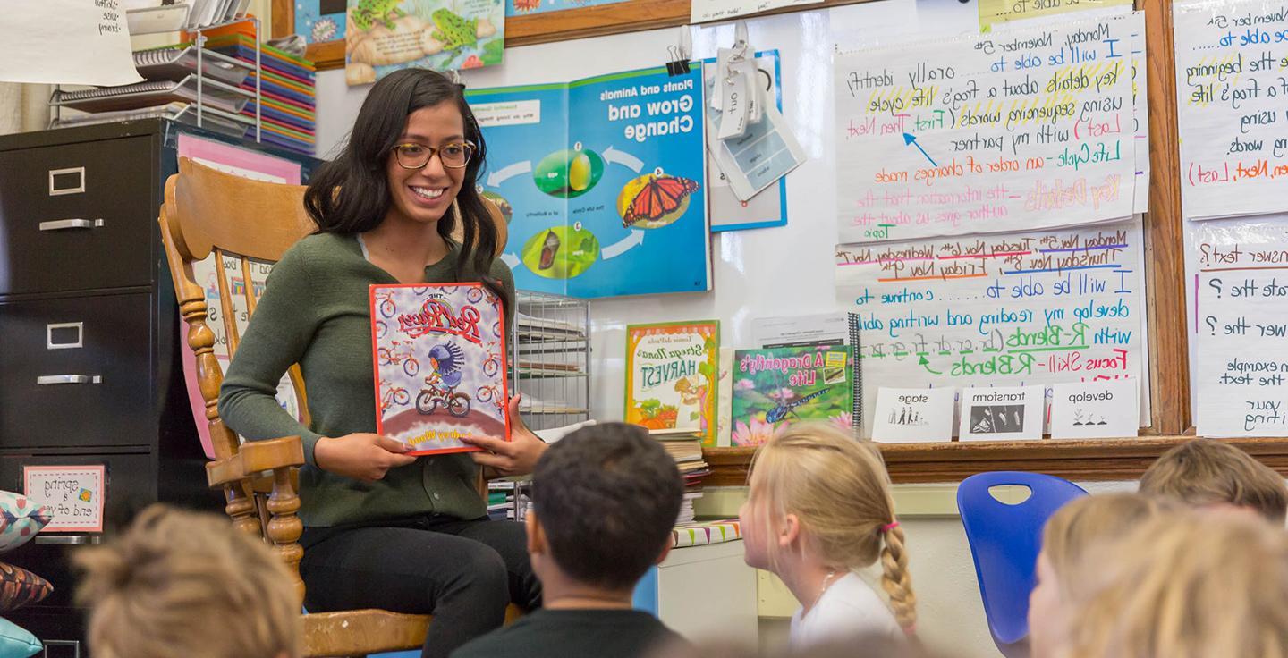 密歇根州立大学丹佛 student Idalee Nunez reading a book to young children in a classroom.