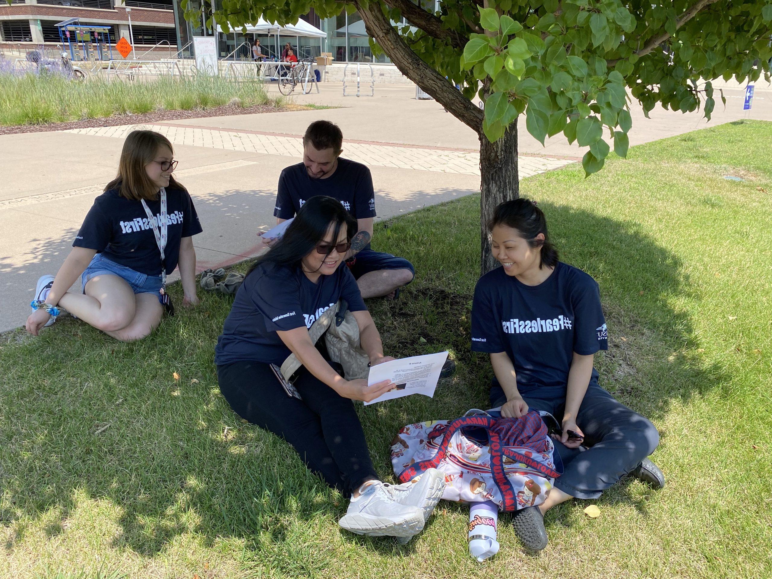 students talking under a tree on campus