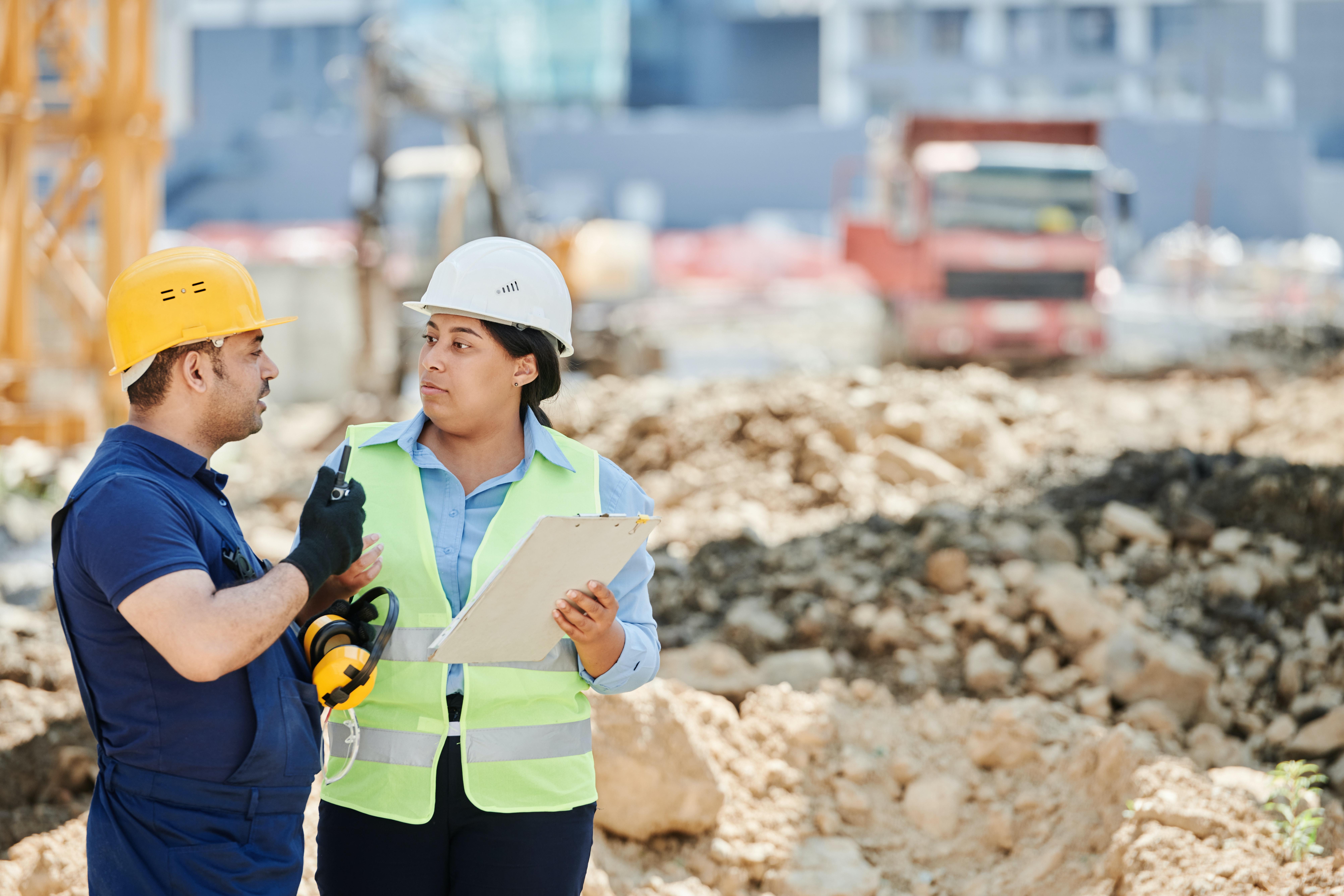 A Man and Woman Wearing Hard Hat While Talking