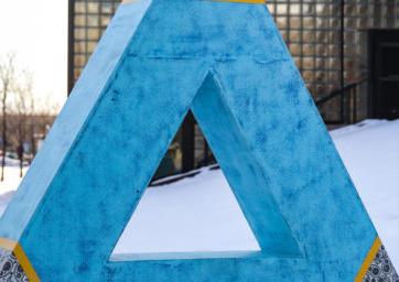 blue 3d triangle with a a triangle hole and black/white paisley corners