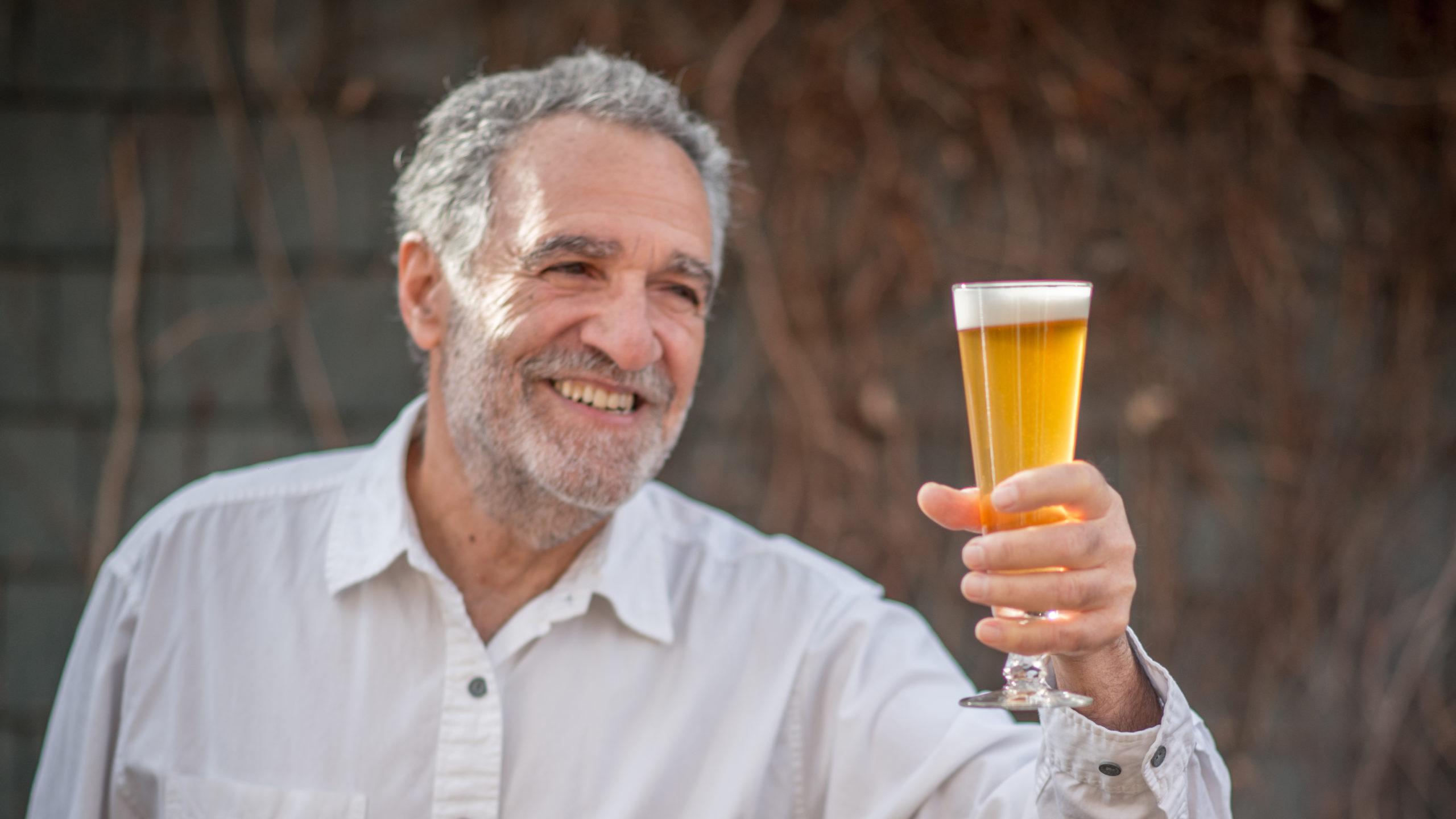 Charlie Papazian holding a beer glass